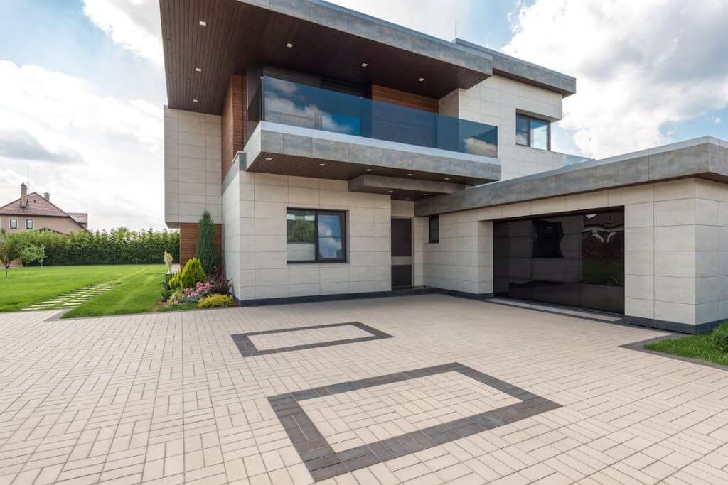 Two story house with glass garage, tiled driveway, and balcony on second floor